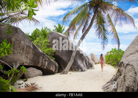 Belle femme posant sur la célèbre source d'argent de la plage de sable blanc avec palmiers, le 27 septembre 2015 dans la passe, la Digu Banque D'Images