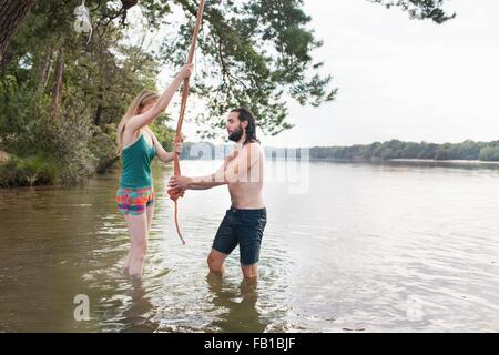 Jeune couple corde se balançant au-dessus du lac Banque D'Images