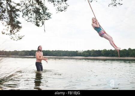 Jeune femme se balancer de corde au-dessus du lac Banque D'Images