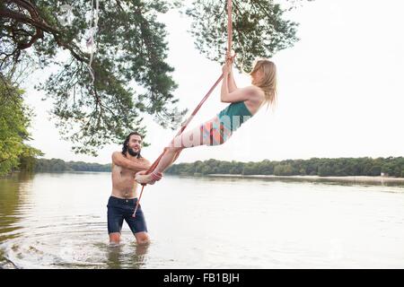 Jeune femme se balancer de corde au-dessus du lac Banque D'Images