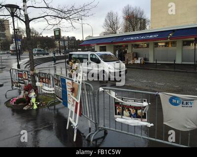 Paris, France. 6 janvier, 2016. Fleurs et bannières commémorer l'attentat terroriste du 9 janvier 2015 à l'Hyper Cacher supermarché cacher à la Porte de Vincennes à Paris, France, 6 janvier 2016. Le 9 janvier 2015 un terroriste a tenu en otage les clients ici et tué quatre personnes. La surveillance d'un véhicule est stationné à l'entrée du magasin. PHOTO : GERD ROTH/DPA/Alamy Live News Banque D'Images