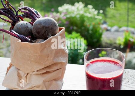 Sac de betterave bio et verre de jus de betteraves rouges sur la table de jardin Banque D'Images