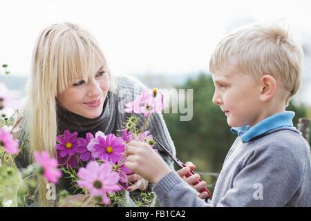 La mère et le fils biologique de coupe flowers in garden Banque D'Images