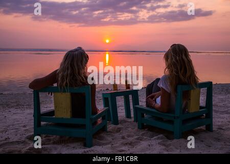 Les femmes qui se découpant en regardant le coucher du soleil sur la mer, Gili Trawangan, Lombok, Indonésie Banque D'Images