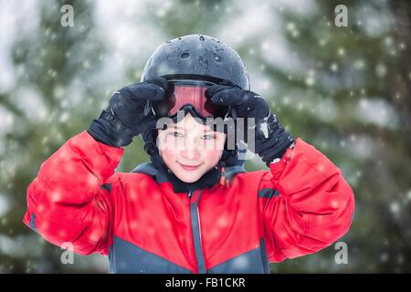 Boy wearing helmet et le ski nocturne à la caméra en souriant, neige Banque D'Images