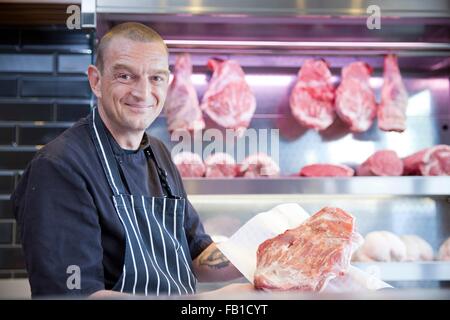 Portrait de butcher holding la viande fraîche en bouchers shop Banque D'Images