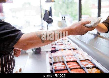 Cropped shot of butcher remise produire au client dans les boucheries shop Banque D'Images