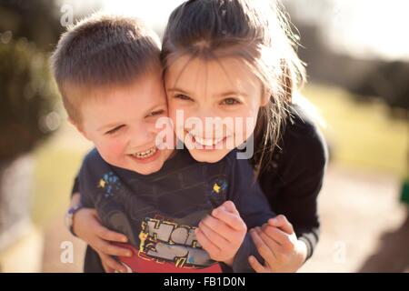 Portrait of Girl hugging frère dans le jardin Banque D'Images