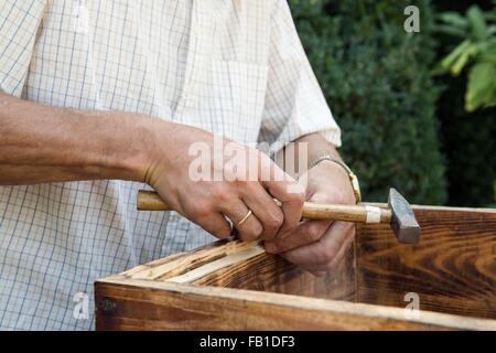 Man faisant des caisses en bois dans jardin, mid section Banque D'Images