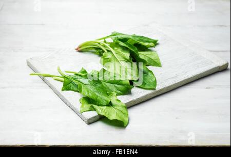 Épinards Feuilles entières sur planche à découper en bois Banque D'Images