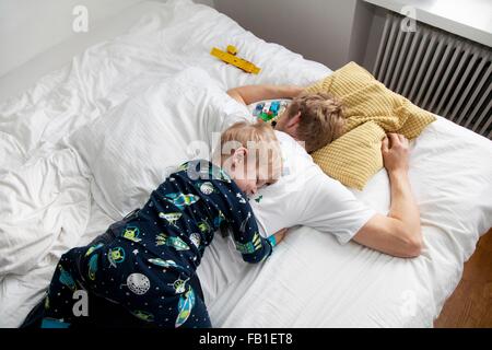 Jeune garçon située au-dessus de lit n père Banque D'Images