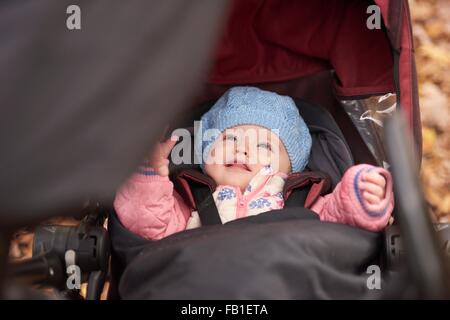 Baby Girl wearing blue hat looking up from baby carriage Banque D'Images