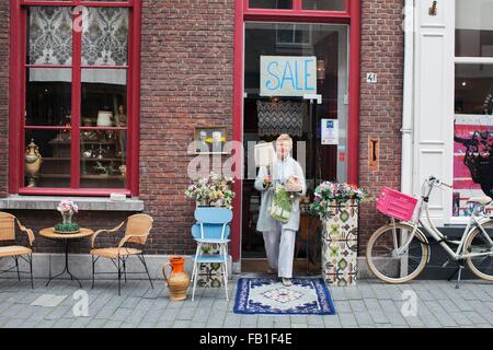 Femelle adulte transportant des clients en dehors de la lampe vintage shop Banque D'Images