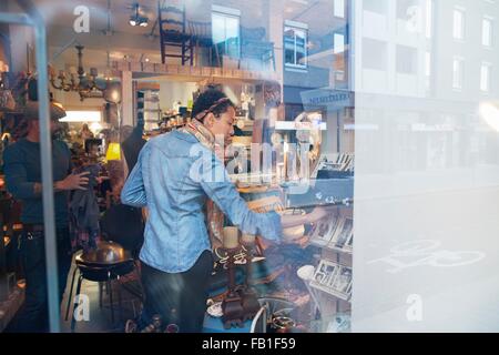 Jeune femme parcourant les vieilles photographies in vintage shop Banque D'Images