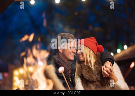 Couple toasting marshmallows à Noël festival à Hyde Park, Londres, UK Banque D'Images