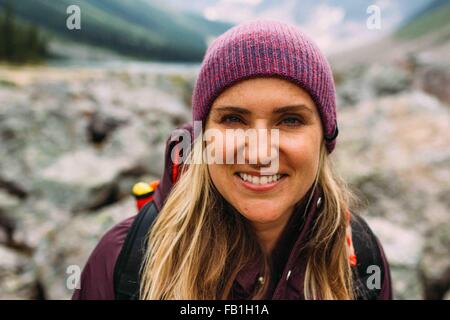 Portrait of mid adult woman wearing Knit hat smiling at camera, lac Moraine, Banff National Park, Alberta Canada Banque D'Images