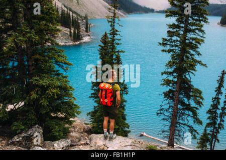 Vue arrière du Mid adult man standing sur le bord de la falaise à la recherche à des vue sur le lac Moraine, Banff National Park, Alberta Canada Banque D'Images