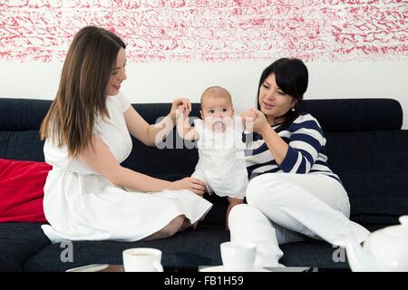 Femme mature et fille jouer avec bébé fille sur le canapé Banque D'Images