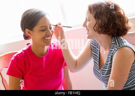 Portrait de jeune femme à l'aide de pinceau à maquillage d'appliquer jusqu'à faire face d'amis Banque D'Images