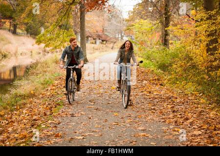 Happy young couple cycling sur riverside en automne Banque D'Images