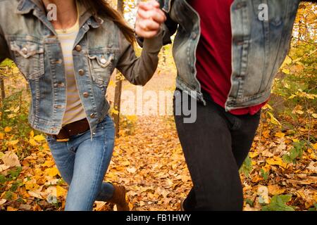 Cropped shot of young couple running through forêt d'automne
