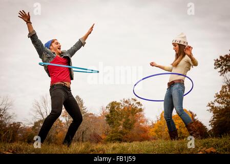 Jeune couple Playing with plastic hoops in autumn park Banque D'Images