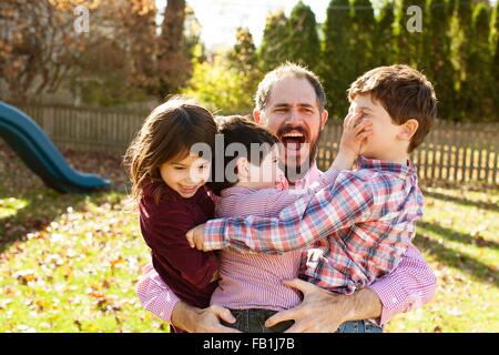 Père transportant les enfants ludique dans ses bras, la bouche ouverte à la surprise Banque D'Images