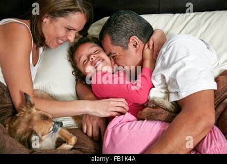 Portrait de jeune fille dans le lit des parents et de son chien, s'étreindre, tickling, smiling Banque D'Images