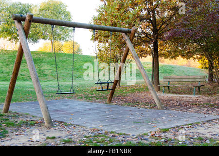 Le Swing et le banc dans un parc avec des feuilles mortes Banque D'Images