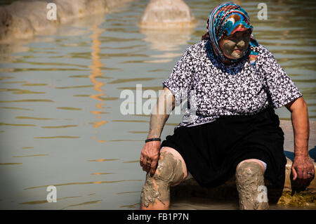 Vieille femme turque avec la boue en face et d'écharpe sur la tête assis à hot spring Banque D'Images