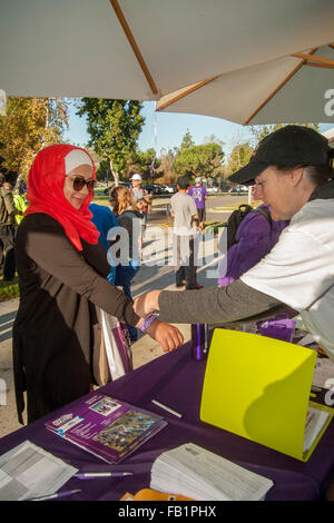 Le port d'un foulard rouge, une femme musulmane reçoit un bracelet d'identification de la part d'un bénévole après avoir fait don de l'argent à une levée de fonds pour les victimes d'Alzheimer à pied dans une Laguna Niguel, CA, Parc. Banque D'Images