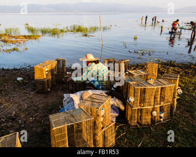 Une femme de la région de la préparation de l'outil de pêche sur le bord du lac. Banque D'Images