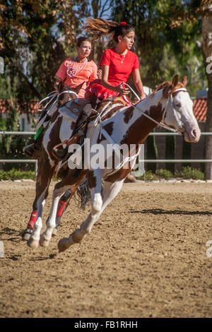 Les jeunes femmes hispaniques montent leurs chevaux au galop à un centre de répondre à Laguna Woods, CA. Banque D'Images