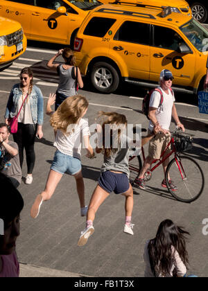 Deux filles de l'adolescence exubérante de sauter les étapes de la ville de New York's Metropolitan Museum of Art de la Cinquième Avenue. Remarque Les taxis et les piétons. Banque D'Images