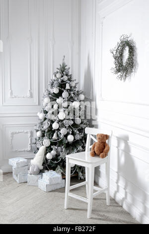 Belle chambre décorée holdiay avec arbre de Noël avec des cadeaux sous elle. Vintage ours siège au président Banque D'Images