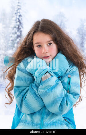 Petite fille en manteau bleu sur fond d'hiver Banque D'Images