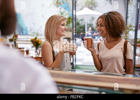 Tourné à l'intérieur de deux jeunes amis féminins ayant une tasse de café au café. Les femmes buvant un café chaud au restaurant de le Banque D'Images