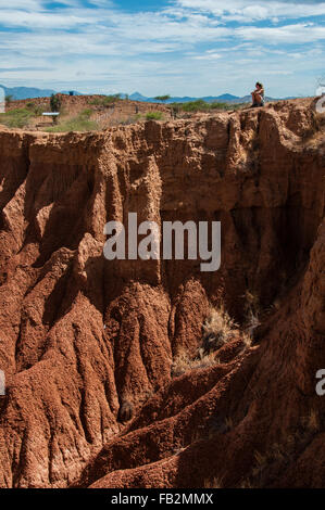Jeune femme blonde assise sur falaise de grès rouge chaud et sec dans le désert Tatacoa, Huila Banque D'Images