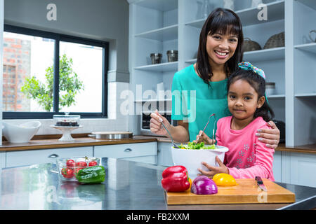 Smiling mother lave-salade avec sa fille Banque D'Images