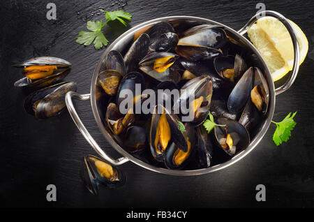 Les moules cuites dans un plat de cuisson sur un fond sombre. Vue d'en haut Banque D'Images