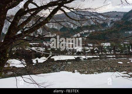 Pont et village couvert de neige dans la montagne, Shirakawa-go, préfecture de Gifu, Japon Banque D'Images