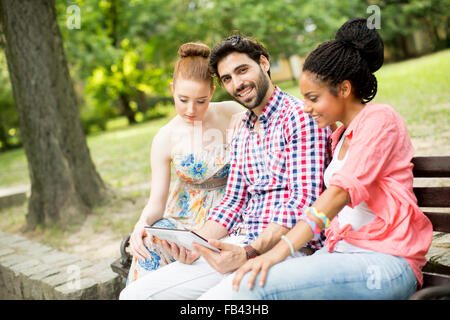 Amis multiraciale, assis sur le banc avec tablet Banque D'Images