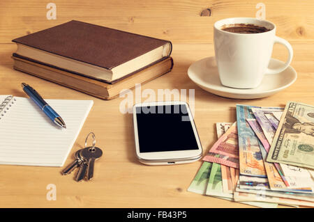 Still Life photo de smart phone, ordinateur portable, bouilloire, un livre, un crayon, de l'argent et les clés sur la table en bois. Focus sélectif. Banque D'Images