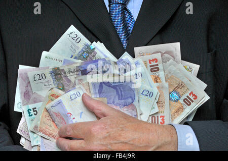 Homme d'affaires en costume et cravate à la main tenant une pile de billets de banque livre sterling image concept pour l'argent dans la main récompense cupidité bonus dépenses d'homme d'affaires Banque D'Images