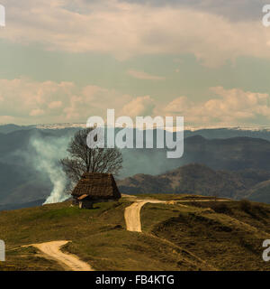 Traditionnelles aménagées dans un paysage de montagnes des Carpates avec de la fumée et les nuages en arrière-plan, Roumanie Banque D'Images