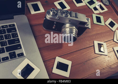 Composition de l'appareil photo à l'ancienne, ordinateur portable et photo diapositives sur table en bois Banque D'Images
