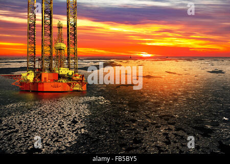 La plate-forme de forage offshore et d'huile dans le lever du soleil sur la mer gelée. Banque D'Images