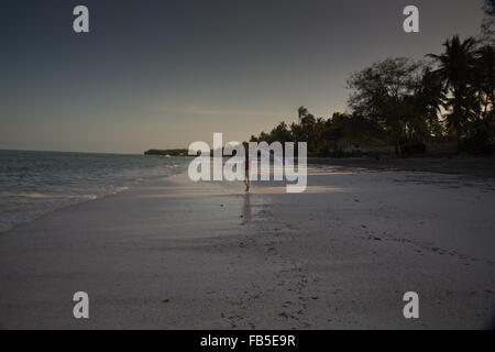 Le dirigeant d'une figure féminine à marcher le long de la plage à Michamwi beach Zanzibar. Banque D'Images