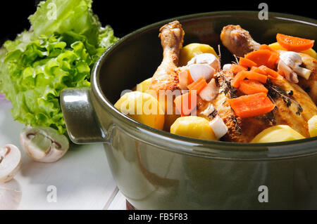 Le poulet, la pomme de terre et carotte avec d'autres légumes en pot en céramique ronde Banque D'Images