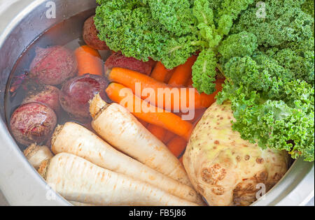 Laver les légumes frais dans un évier de cuisine. Banque D'Images